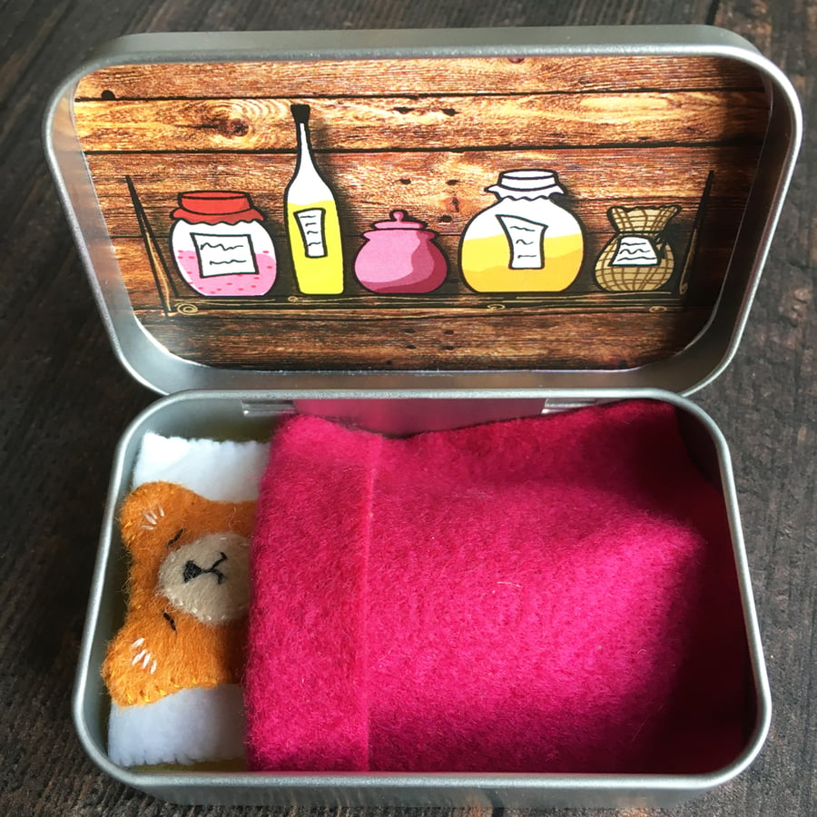 Tiny felt teddy asleep in a tin.