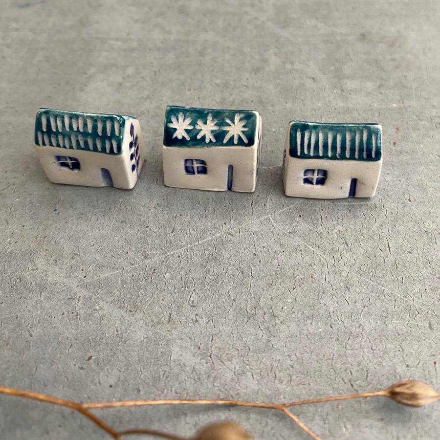 Set of three tiny ceramic houses .
