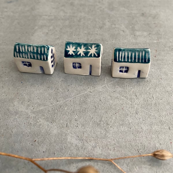 Set of three tiny ceramic houses .