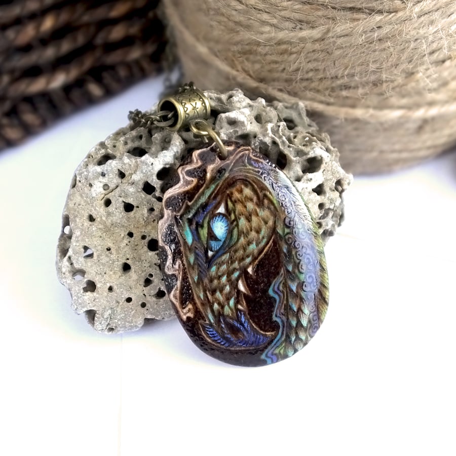 Moody blue dragon. Pyrography wooden teardrop pendant in peacock colours.