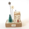 Little wooden house with Christmas tree, star and button