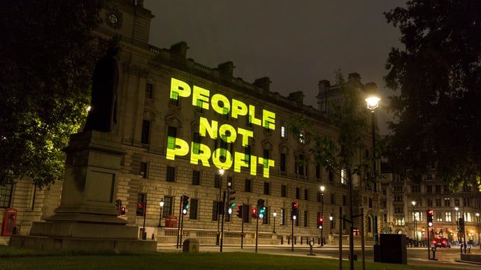 "people not profit" projected on a building