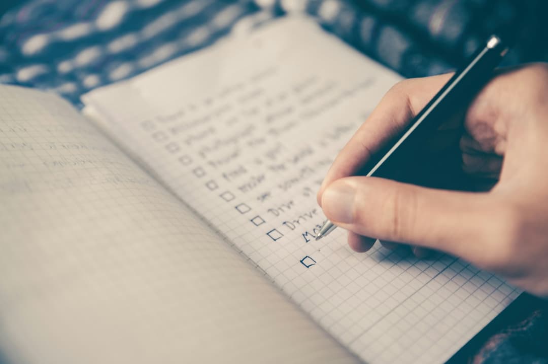 A hand writing a to-do list in a notebook