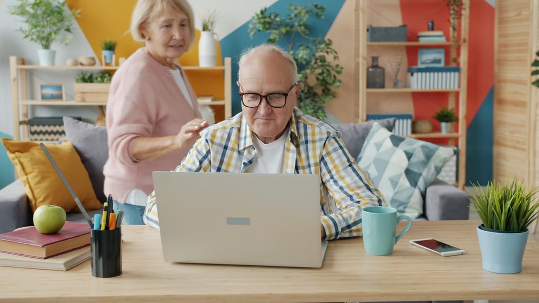 Senior couple smiling while using a laptop at home