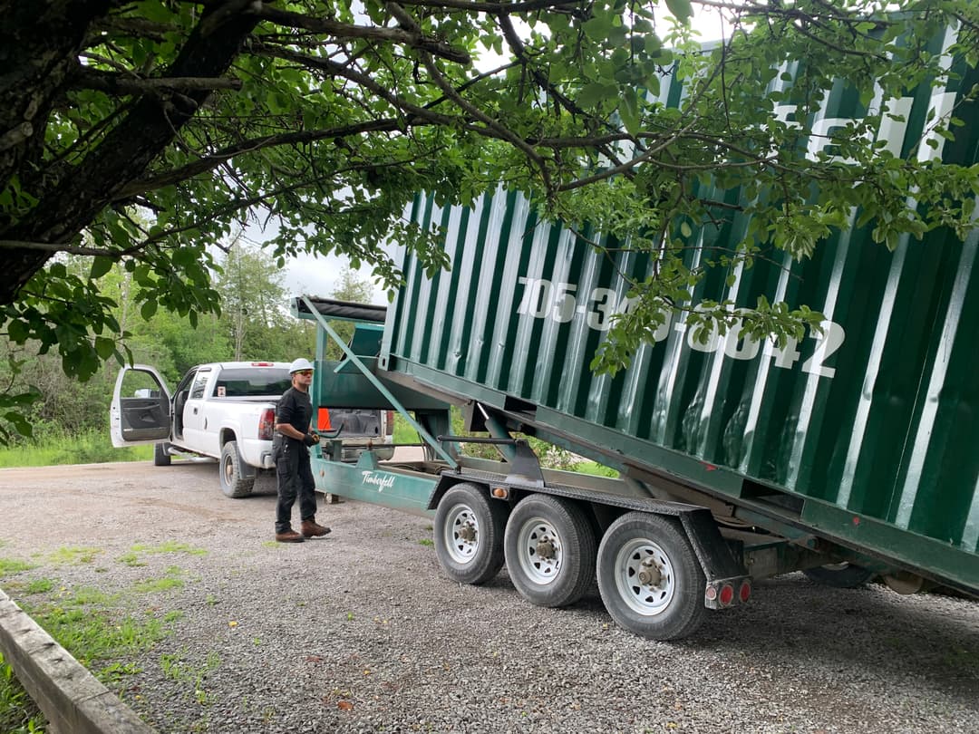 Storage container being unloaded from the Timberfell trailer on a gravel driveway