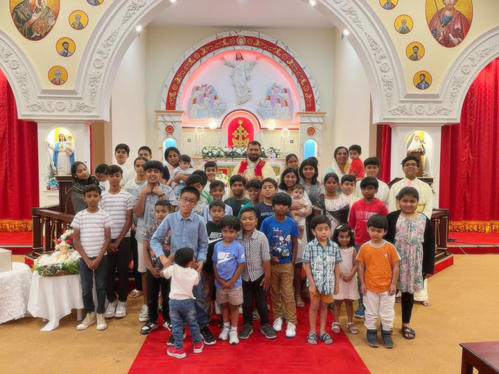 Children in white and red praying together in church