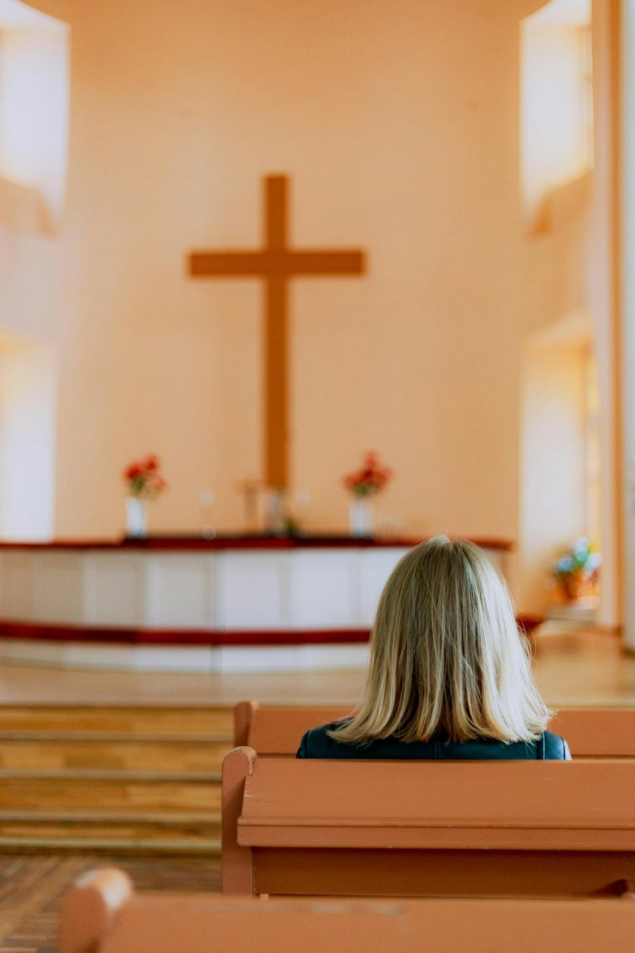A person praying before a cross in a bright chapel