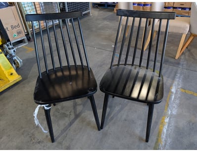 Pair of black dining chairs featuring a modern spi...