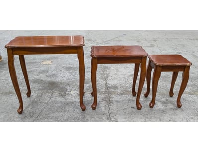 A charming three-piece nesting table set in warm m...
