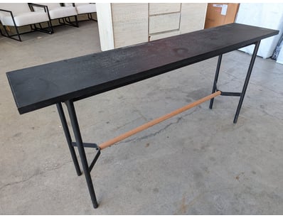 Console table featuring a charcoal-finished wood t...