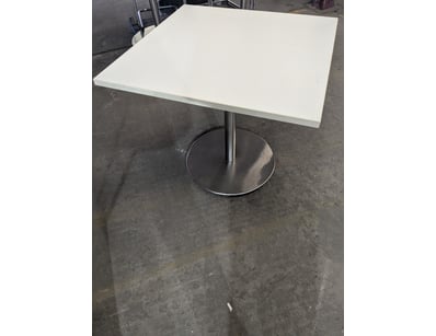 Modern pedestal dining table featuring a white lam...