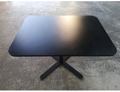 Black pedestal dining table featuring a rounded re...