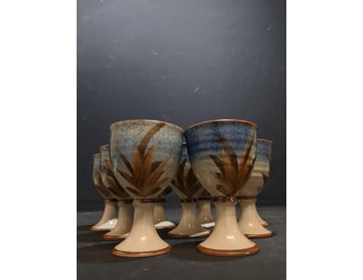 A striking set of nine ceramic goblets featuring a...