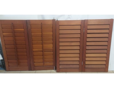Set of two wooden louvered shutters featuring adju...