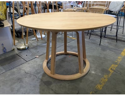 Elegant round dining table featuring a light ash w...