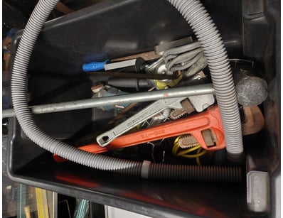 Black plastic toolbox containing assorted hand too...