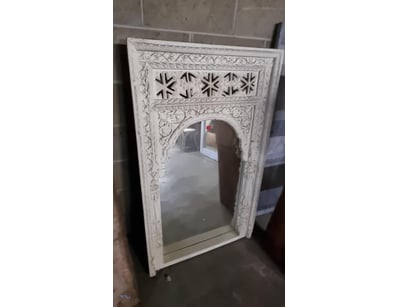 Ornate white-painted decorative mirror featuring a...