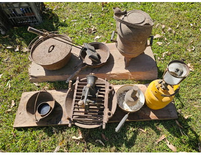 Assorted vintage cast iron cooking equipment on wo...