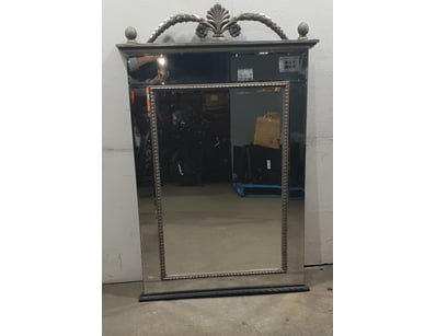 Ornamental wall mirror featuring a classical desig...