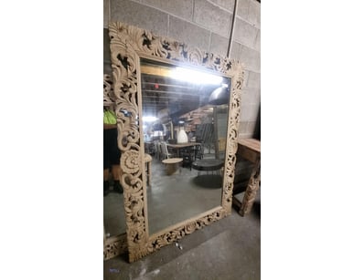 Ornately carved wooden framed mirror featuring ela...