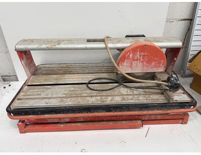 Vintage electric tile cutter featuring a red metal...