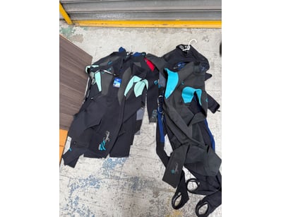 Bulk lot of wetsuits in various sizes and styles. ...