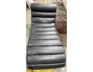 Modern black leather chaise lounge featuring a con...