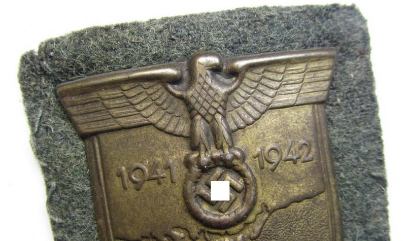 Attractive, WH (Heeres o. Waffen-SS) 'Krim'-campaign-shield that comes mounted onto its original, field-grey-coloured 'backing' and that comes in an issued-, minimally worn and/or carefully tunic-removed-, condition