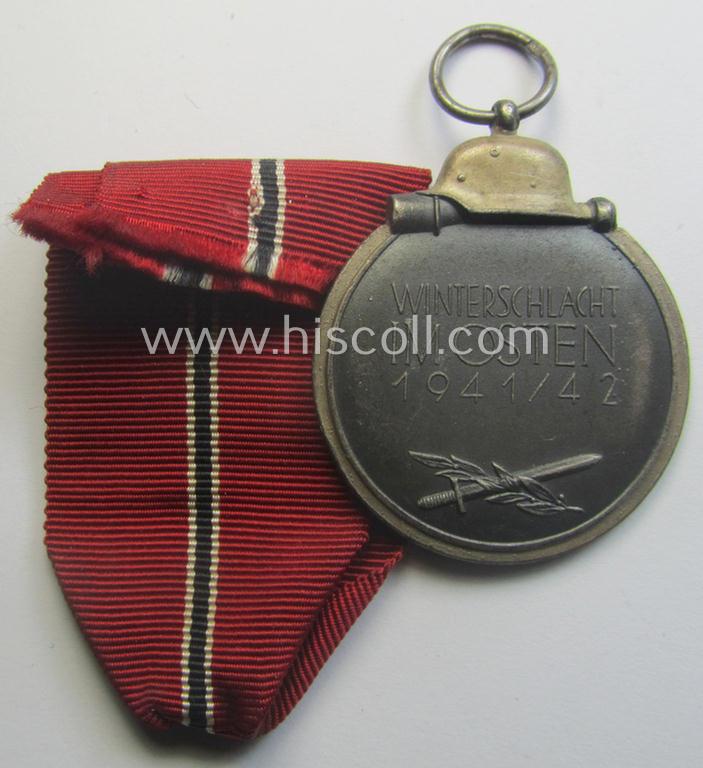 Medal-set: 'Winterschlacht im Osten 1941-42' being a maker- (ie. '93'-) marked- (and/or 'Feinzink'-based) specimen by the maker: 'Richard Simm & Söhne' and that comes together with its (minimally confectioned) ribbon (ie. 'Bandabschnitt')