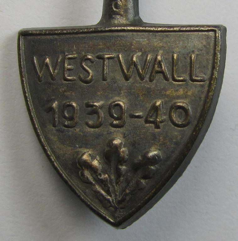 Neat, silver-toned, commemorative- and typical zinc- (ie. tin-) based day-badge (ie. 'tinnie') that comes in the format of a spade and depicting the text: 'Westwall 1939-40'