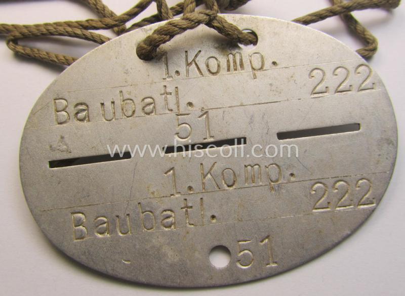 Aluminium-based, WH (Heeres) ie. 'Pioniere- o. Bau-Truppen'-related ID-disc bearing the clearly stamped unit-designation: '1. Komp.Baubatl. 222' and that comes mounted on its period cord as issued and worn