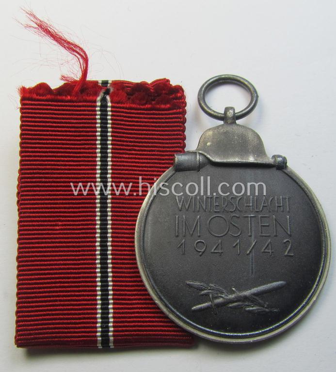 Attractive medal-set: 'Winterschlacht im Osten 1941-42' being a maker- (ie. '127'-) marked- (and/or 'Feinzink'-based) specimen by the maker: 'Moritz Hausch A.G.' and that comes together with its (non-confectioned) ribbon (ie. 'Bandabschnitt...