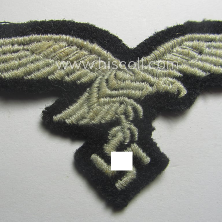 Minimally used, WH (Luftwaffe) cap-eagle (being a 'standard-issue'-pattern example that is executed onto a black-coloured background and that was as such intended for usage on the black-coloured work- ie. 'HG'-related side-caps ie. 'Schiffchen')
