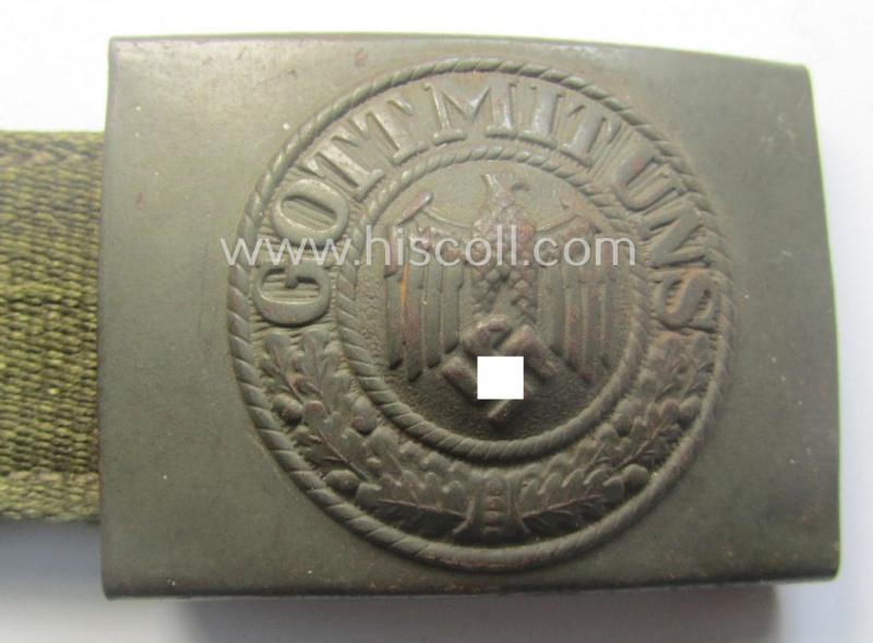 WH (Heeres) 'tropical-issued' belt-buckle being a clearly maker- (ie. 'HA'-) marked (and/or: '42'-dated) field-grey-coloured example that comes mounted onto its original, greenish-coloured- (and/or: 'webbing'-based-) tab