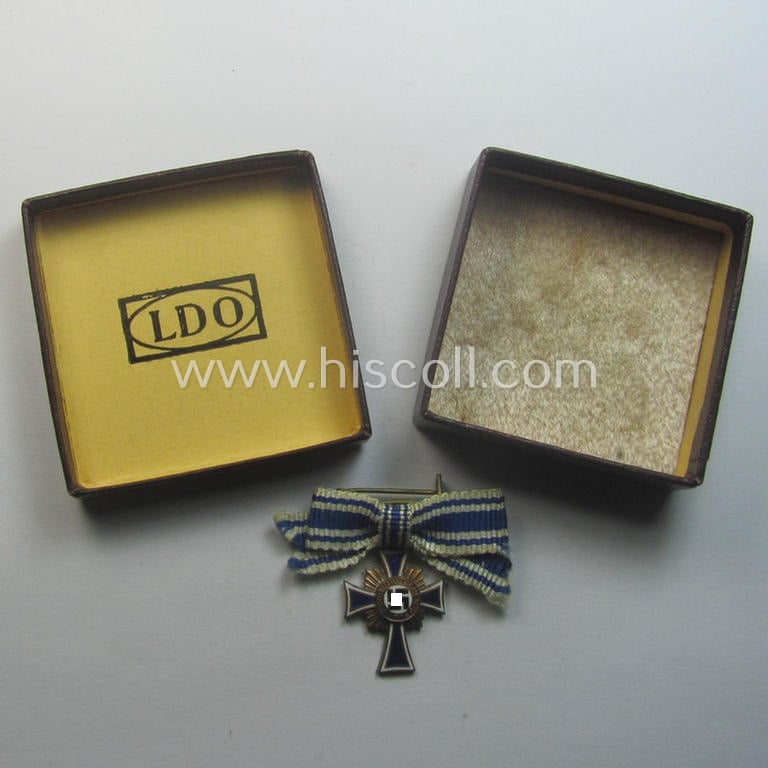 Attractive, 2-cms.-sized miniature of a maker- (ie. 'L/60'- ie. by 'GB'-) marked: 'Ehrenkreuz der Deutschen Mutter in Bronze' that came stored in its non-maker-marked, two-pieced bordeaux-coloured 'LDO'-type box (ie. etui)
