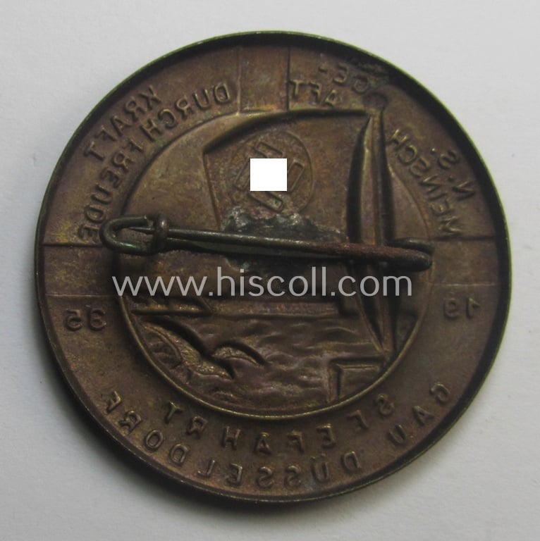 Attractive, so-called: 'KdF'- ('DAF- o. Kraft durch Freude'-) related day-badge (ie. 'tinnie') depicting a large vessel ie. cruise-ship, swastika-flag  and text that reads: 'N.S. Gemeinschaft Kraft durch Freude - Seefahrt - Gau Düsseldorf - 1935'