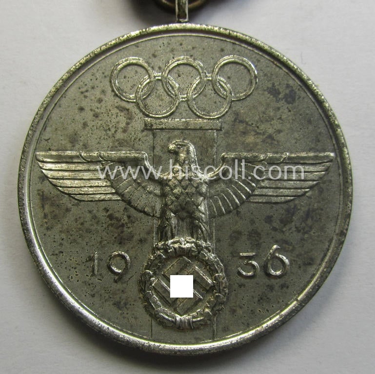 'Deutsche Olympia-Erinnerungsmedaille 1936' being a non-maker-marked example that comes mounted onto its original ribbon (ie. 'Bandabschnitt') and that comes stored in its typical, beige-white-coloured etui