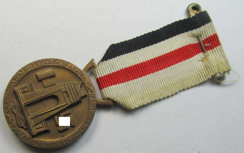 Superb, golden-bronze-coloured- (and I deem 'Buntmetall'-based-) example of a: 'Deutsch-Italienische Feldzugsmedaille' (or: German-Italian campaign medal) that comes mounted onto its (regular-sized) piece of original (albeit minimally faded) ribb...