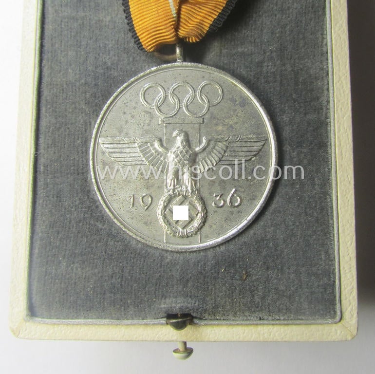 'Deutsche Olympia-Erinnerungsmedaille 1936' being a non-maker-marked example that comes mounted onto its original ribbon (ie. 'Bandabschnitt') and that comes stored in its typical, beige-white-coloured etui