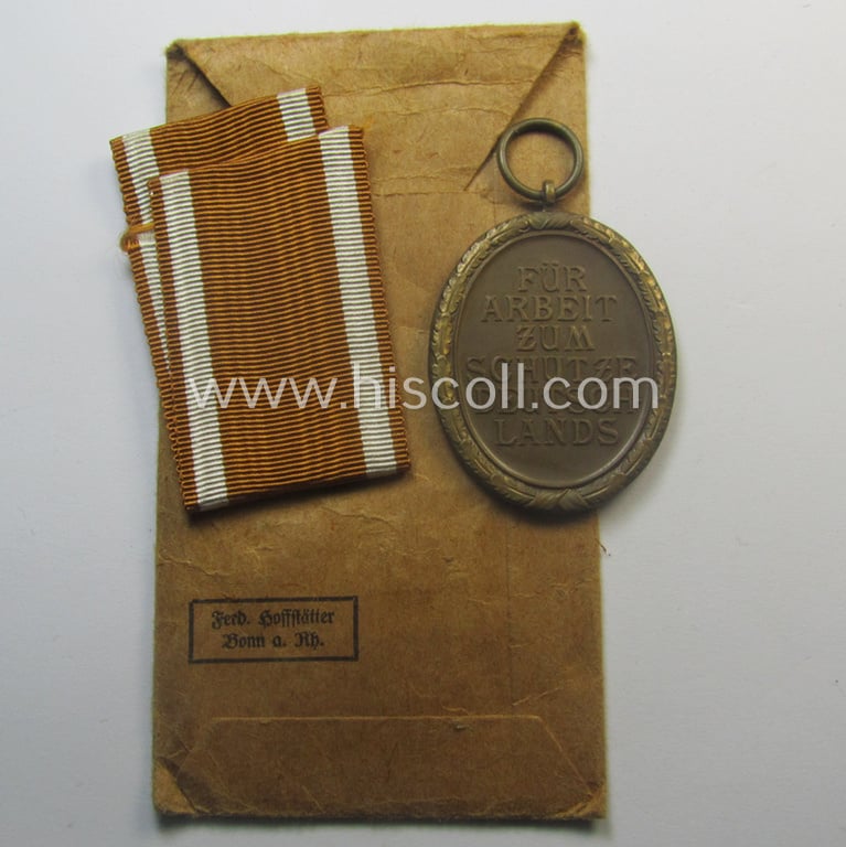 Medal-set: 'Deutsches Schutzwall Ehrenzeichen' (aka: 'Westwall'-medal) being a (typical) non-maker-marked- and/or: typical 'Buntmetall'-based specimen that comes packed in its original pouch of issue by the: 'Ferd. Hoffstätter'-company