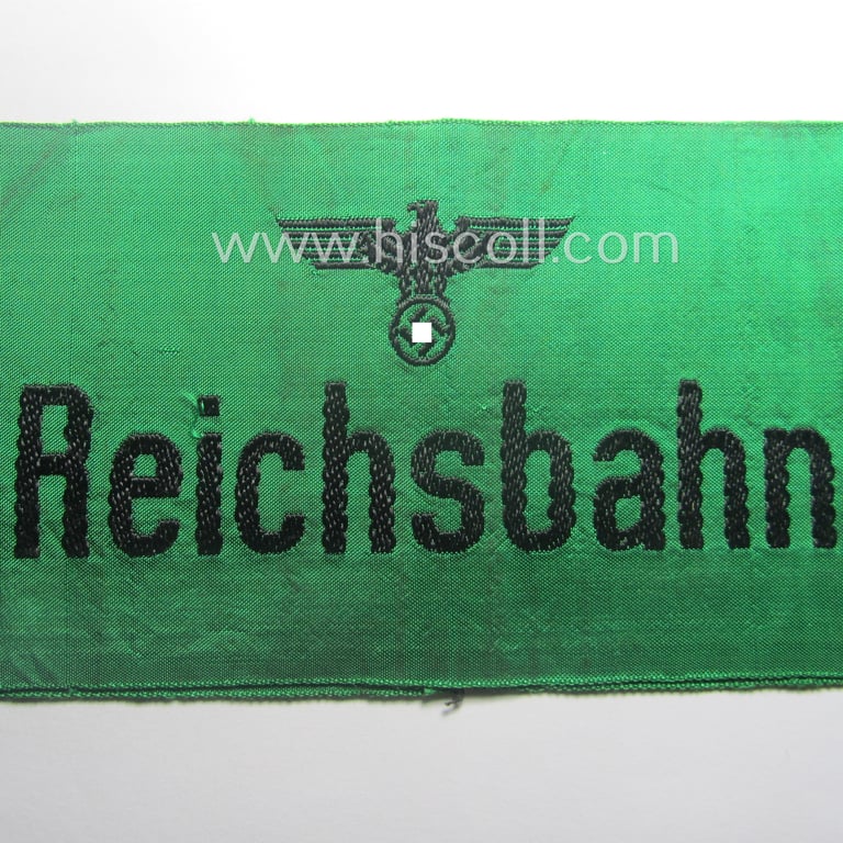 DRB- (ie. 'Deutsche Reichsbahn'-) related armband entitled: 'Reichsbahn' being of the 'entirely-woven'-type onto (typical shiny) 'silk-like' cloth in a technique similar to the 'BeVo'-weave pattern