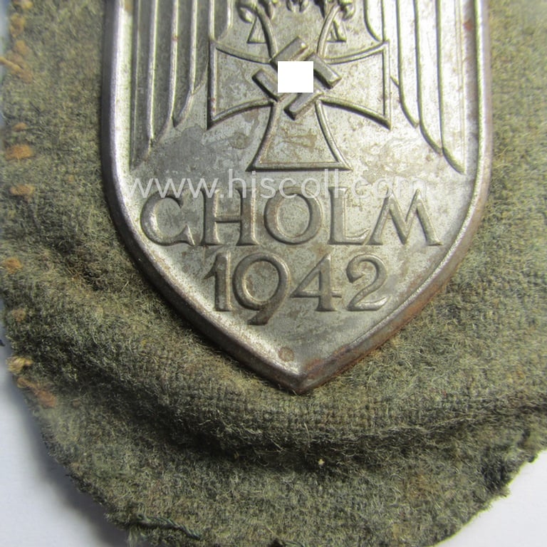 Stunning - and truly rarely encountered! - WH (Heeres ie. Waffen-SS) so-called: 'Cholm'-campaign-shield as executed in magnetic, so-called: 'Eisenblech' being a 'Long M-variant-pattern' shield that comes in a moderately used- ie. worn-, condition