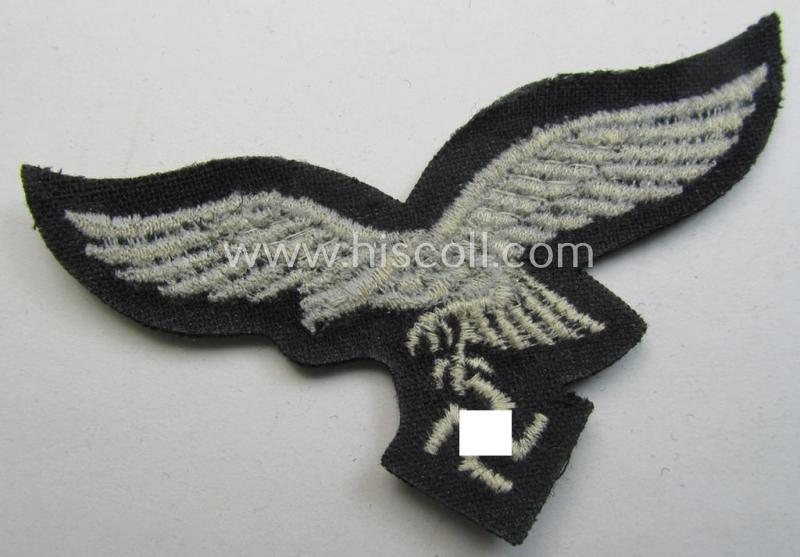 WH (Luftwaffe) cap-eagle (being a 'standard-issue'-pattern example that is executed onto a black-coloured background and that was as such intended for usage on the black-coloured work- ie. 'HG'-related side-caps ie. 'Schiffchen')