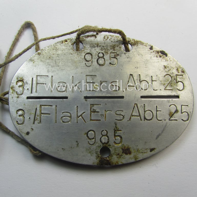 Aluminium-based, WH (Luftwaffe) ie. 'LW-Flak-Artillerie'-related ID-disc (ie. 'Erkennungsmarke') bearing the stamped unit-designation: '3./Flak Ers.Abt. 25' and that comes mounted onto its cord as issued- and/or worn
