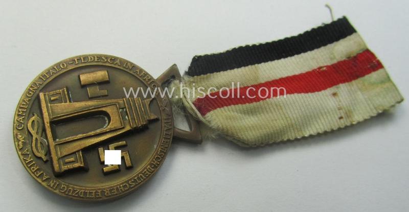 Golden-bronze-coloured- (and I deem 'Buntmetall'-based-) example of a: 'Deutsch-Italienische Feldzugsmedaille' (or: German-Italian campaign-medal) that comes mounted onto its (regular-sized) piece of original (and sun-faded!) ribbon