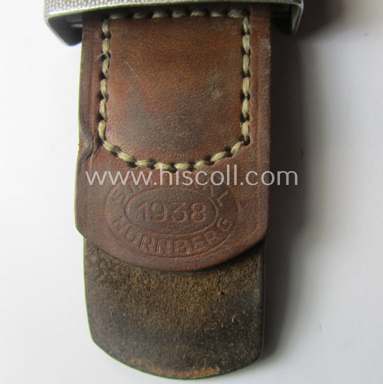 Moderately used WH (Heeres) 'standard-pattern', silver-toned- and aluminium-based belt-buckle being a maker- (ie. 'St.Merkl - Nürnberg'-) marked- and/or: '1938'-dated example that comes mounted onto its leather-based tab
