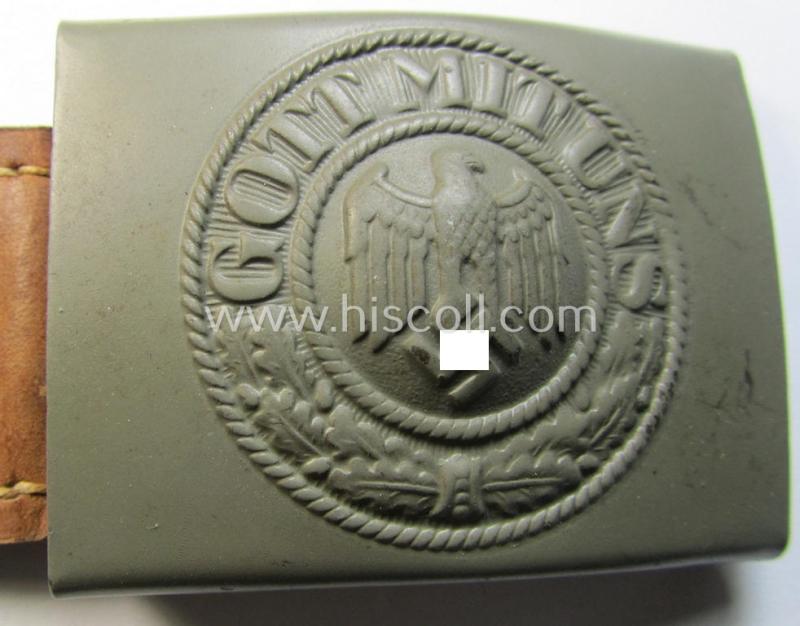 Superb, WH (Heeres) field-grey-coloured- and/or steel-based belt-buckle being (an unusally seen!) non-maker-marked- nor dated example that comes mounted onto its (light-brown-coloured) leather-based tab and that comes in a wonderful condition