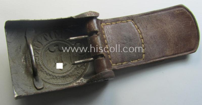 Moderately used, WH (Heeres) field-grey-coloured- and/or steel-based belt-buckle being a non-maker-marked example that comes mounted onto its maker- (ie. 'F.W. Assmann - Lüdenscheid'-) marked and/or '1940'-dated leather-based tab