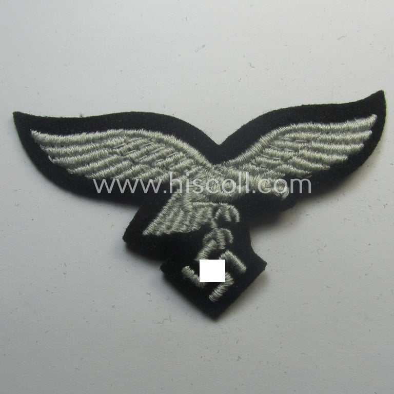 WH (Luftwaffe) cap-eagle (being a 'standard-issue'-pattern example that is executed onto a black-coloured background and that was as such intended for usage on the black-coloured work- ie. 'HG'-related side-caps ie. 'Schiffchen')