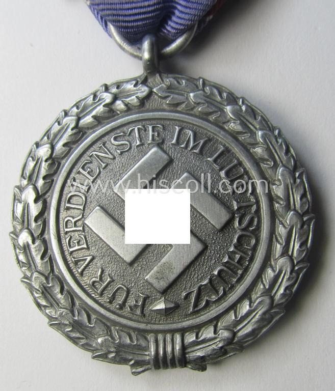 'Luftschutz-Ehrenzeichen 2. Stufe' being a maker- (ie. '10'-) marked example, as executed in (heavy) zinc-based metal (ie. 'Feinzink') and that came together with its period ribbon (ie. 'Bandabschnitt')